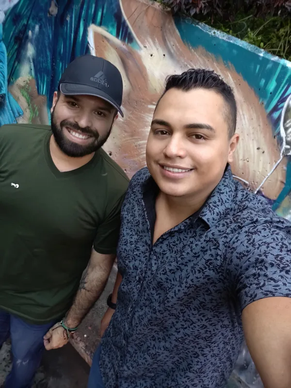 Selfie de dos compañeros frente a un mural de colores